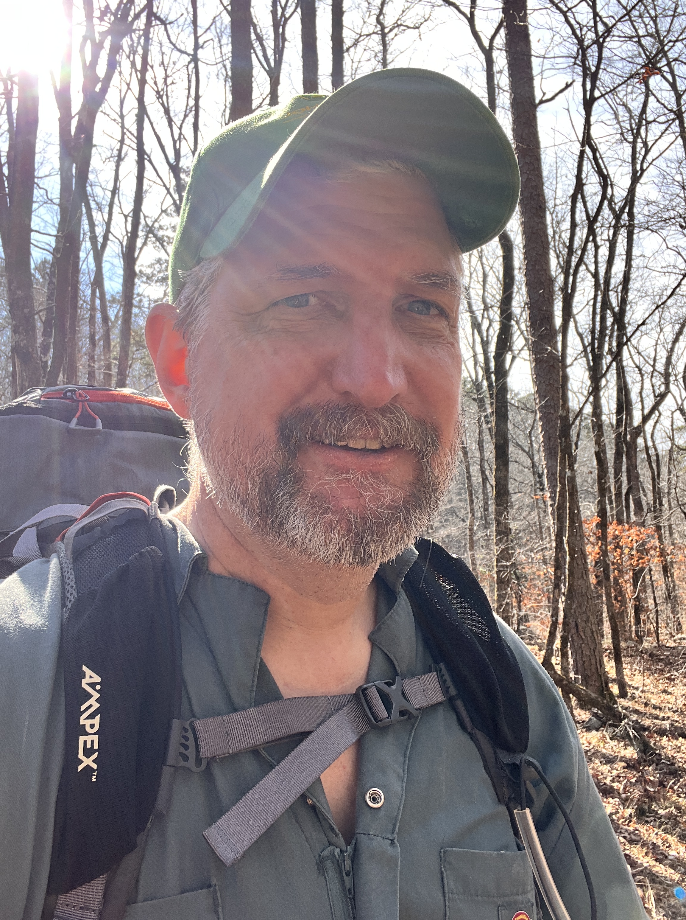 A man wearing a backpack and standing in the woods